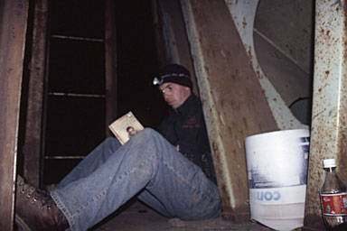 Reading by flashlight on the rear porch of a grain car